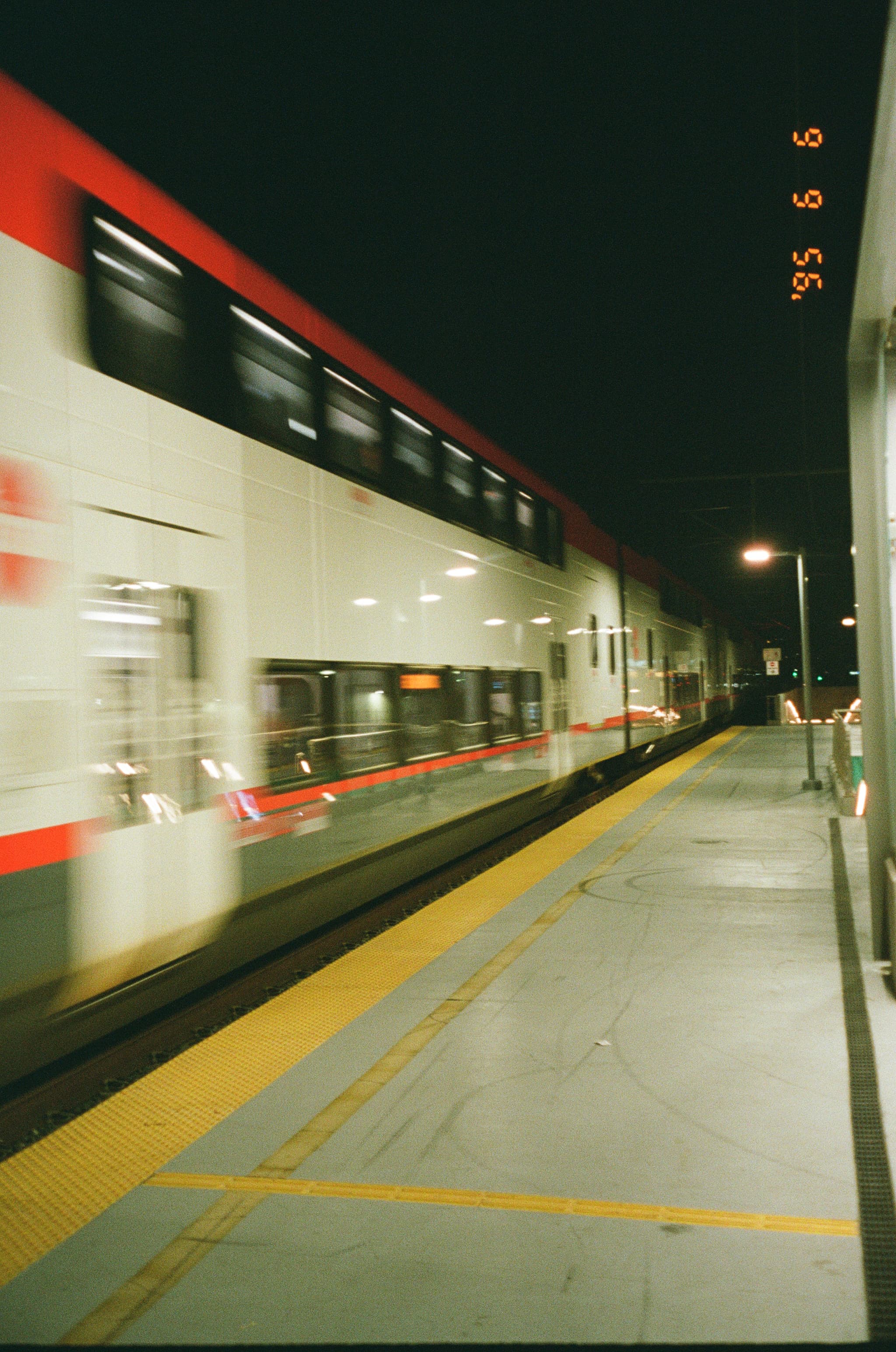 A train moving quickly through a dimly lit station at night, with a blurred effect indicating motion